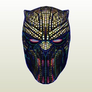 Könnte beinhalten: Eine schwarze und goldene Papiermaske mit geometrischem Muster. Die Maske hat ein spitzes Kinn und einen erhöhten Nasenrücken. Die Augen sind blau umrandet und der Mund ist rot umrandet.