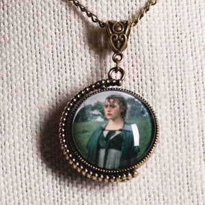 May include: A bronze necklace with a round glass pendant featuring a woman in a green dress. The pendant is surrounded by a decorative bronze border.