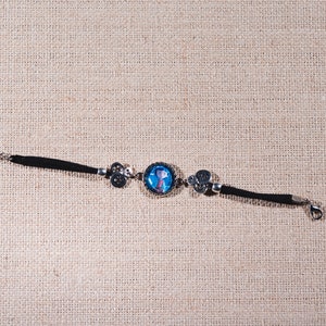 Peut inclure: Un bracelet en cuir noir avec un charme argent&eacute; repr&eacute;sentant un personnage de dessin anim&eacute; bleu et blanc. Le bracelet est dot&eacute; d'un fermoir argent&eacute;.