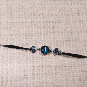 Peut inclure: Un bracelet noir avec un charme argent&eacute; repr&eacute;sentant un squelette bleu et blanc. Le bracelet a un fermoir argent&eacute;.