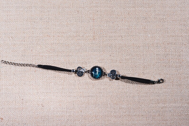 Peut inclure: Un bracelet noir avec un charme argent&eacute; repr&eacute;sentant un squelette bleu et blanc. Le bracelet a un fermoir argent&eacute;.