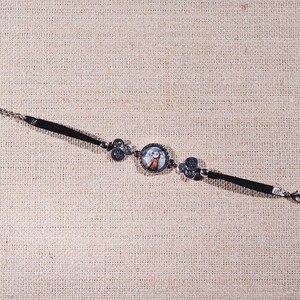 Peut inclure: Un bracelet noir avec un charme argent&eacute; repr&eacute;sentant une fille de dessin anim&eacute;. Le bracelet a une fermeture &agrave; cha&icirc;ne.