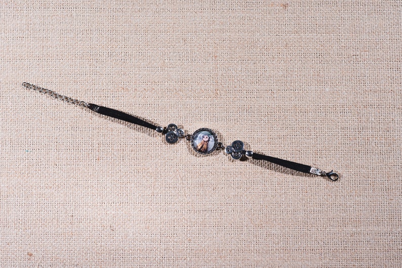 Peut inclure: Un bracelet noir avec un charme argent&eacute; repr&eacute;sentant une fille de dessin anim&eacute;. Le bracelet a une fermeture &agrave; cha&icirc;ne.
