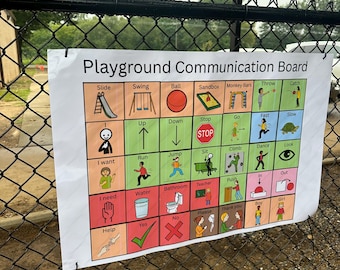 May include: A white Playground Communication Board with colorful illustrations and text, including "Slide," "Swing," and "Ball." The board is attached to a chain-link fence, designed for communication.