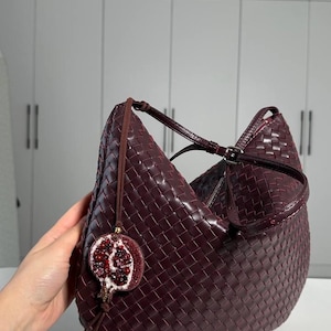 trendiger Taschenaccessoire funkelnder Granatapfel bordeauxfarbender Granatapfel Statement stück modischer Taschenbaumler Statementschmuck Taschenbaumler Handtaschenschmuck