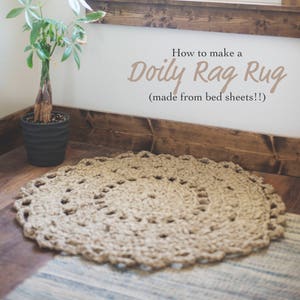 May include: A close-up of a beige crocheted doily rug with a brown wooden trim and a potted plant in the background. The text "How to make a Doily Rag Rug (made from bed sheets!!)" is written on the wall.