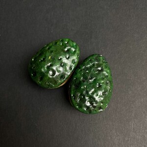 May include: Two green avocado-shaped ceramic ornaments with a textured surface.