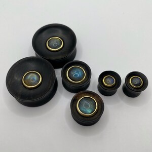 Concave ebony wood plugs with labradorite inlay. Labradorite cabochons of these ebony concave plugs are set in brass bezels. Can be made in sizes from 10mm to 30mm. Each labradorite cabochon inlay is unique