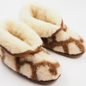 May include: A pair of brown and white wool slippers with a fuzzy lining. The slippers have a geometric pattern.