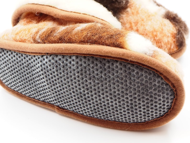 May include: Close-up of the bottom of a brown and white patterned slipper with a gray textured sole.