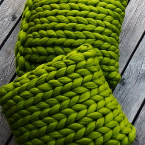 May include: Two large, green, chunky knit throw pillows. The pillows are made of thick yarn and have a soft, fuzzy texture.