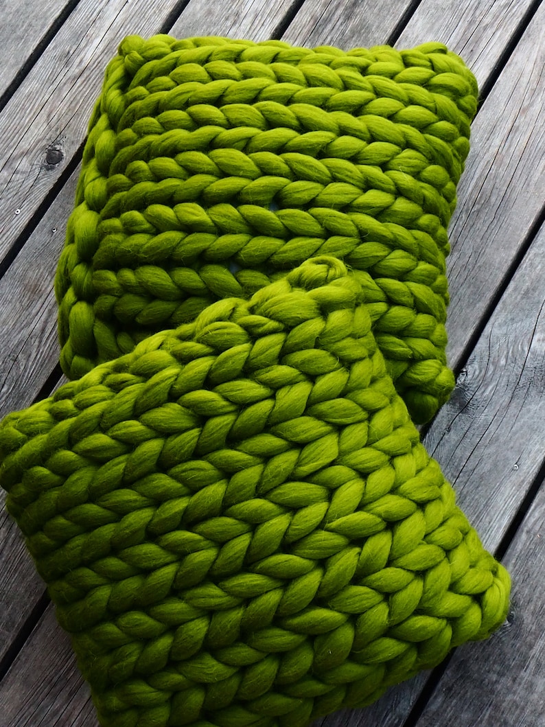 May include: Two large, green, chunky knit throw pillows. The pillows are made of thick yarn and have a soft, fuzzy texture.