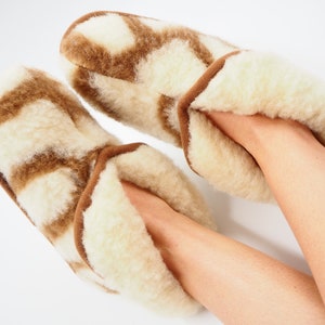 May include: Pair of brown and white patterned sheepskin slippers with a fluffy interior.