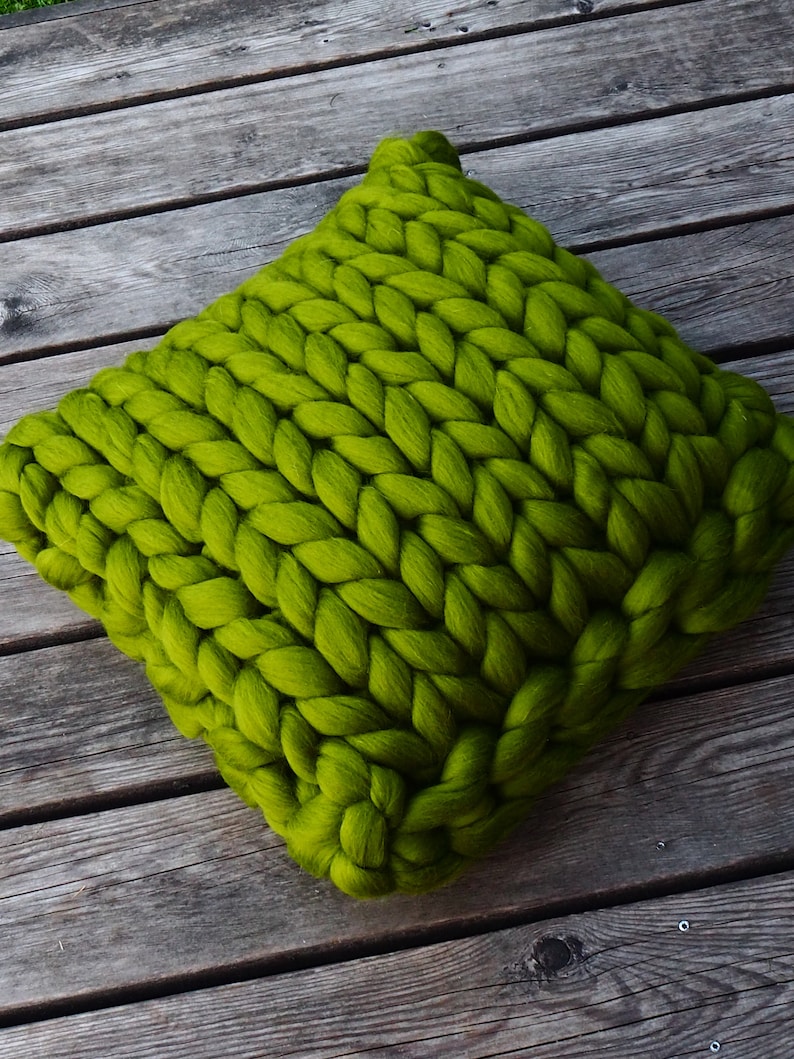 May include: A large, chunky knit pillow in a bright green color. The pillow is made of thick yarn and has a soft, cozy texture.