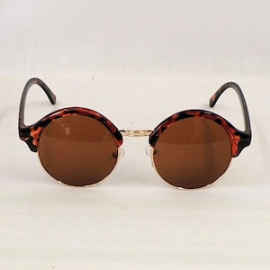 May include: Brown tortoiseshell round sunglasses with brown lenses.