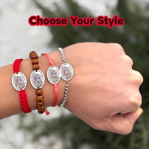 Puede incluir: Cuatro pulseras con colgantes ovalados con una imagen religiosa. Las pulseras var&iacute;an en estilo: cord&oacute;n trenzado rojo, cuentas de madera, cord&oacute;n coral y una cadena de plata. El texto "Choose Your Style" se muestra en rojo.