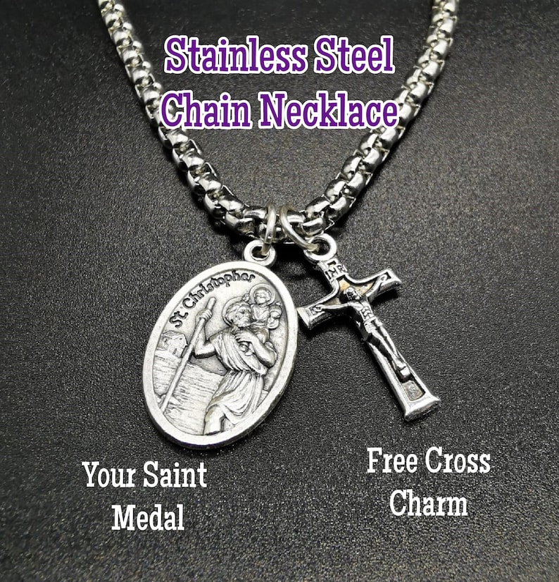 May include: Stainless steel chain necklace with a silver St. Christopher medal and a silver cross charm. The medal features a depiction of St. Christopher carrying a child. The cross charm has a figure of Jesus on it.
