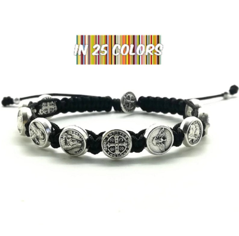 May include: Black braided bracelet with silver charms featuring religious imagery. The bracelet has a sliding knot closure. "IN 25 COLORS" is written on a colorful striped background.