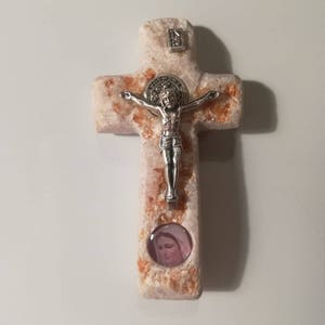 K&ouml;nnte beinhalten: Ein wei&szlig;es Steinkreuz mit einer silbernen Jesusfigur und einem runden Bild der Jungfrau Maria. Das Kreuz hat oben eine kleine Inschrift "IN RI".