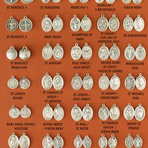 May include: A collection of 24 silver oval-shaped religious medallions featuring various saints, including St. Benedict, St. Anthony, St. Joseph, St. Francis of Assisi, and the Virgin Mary. Each medallion has a different image and inscription.