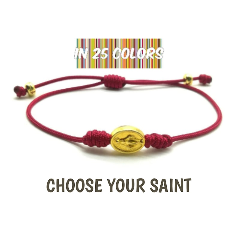 May include: Red string bracelet with a gold oval charm featuring a religious figure. The bracelet is adjustable and comes in 25 colors. "Choose Your Saint" text is displayed below the bracelet.