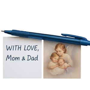 Puede incluir: Un bol&iacute;grafo azul oscuro descansa sobre dos im&aacute;genes. Una presenta el texto "WITH LOVE, Mom & Dad". La otra es una pintura de tres figuras querubinas. El fondo es blanco.
