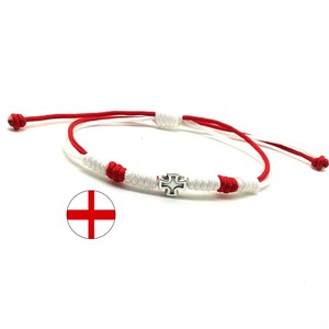 May include: Red and white braided bracelet with a silver cross charm. The bracelet is adjustable and has a sliding knot closure.