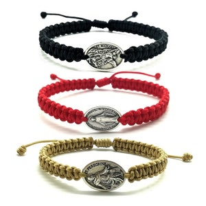 May include: Three braided cord bracelets with silver oval charms. The charms feature religious imagery and text. The bracelets are black, red, and gold.