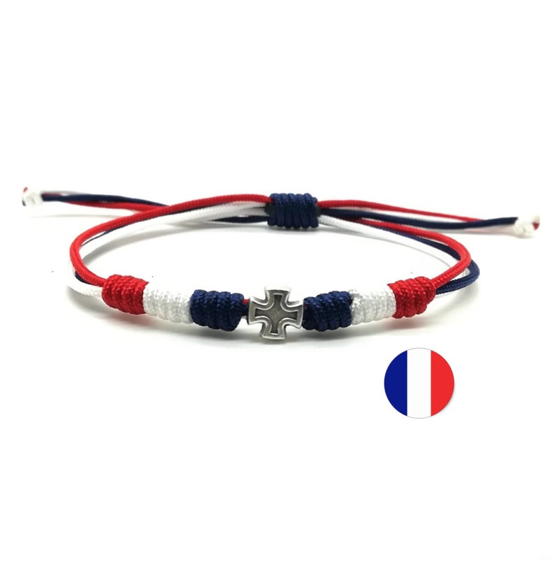 May include: A red, white, and blue braided bracelet with a silver cross charm. The bracelet is tied with a knot and has a tassel on the end.
