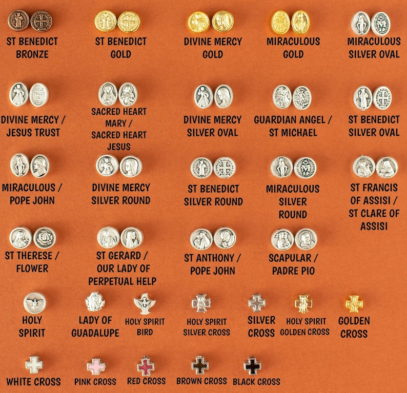 May include: A collection of 20 round metal medallions with various religious figures and symbols. The medallions are arranged in rows on a brown background. The medallions are made of silver, gold, and bronze. The text on the medallions includes names like St. Benedict, Divine Mercy, and Miraculous.