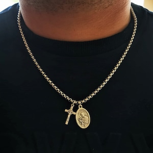 Puede incluir: Un collar de cadena de plata con una cruz de plata y un colgante ovalado de plata con una figura religiosa.