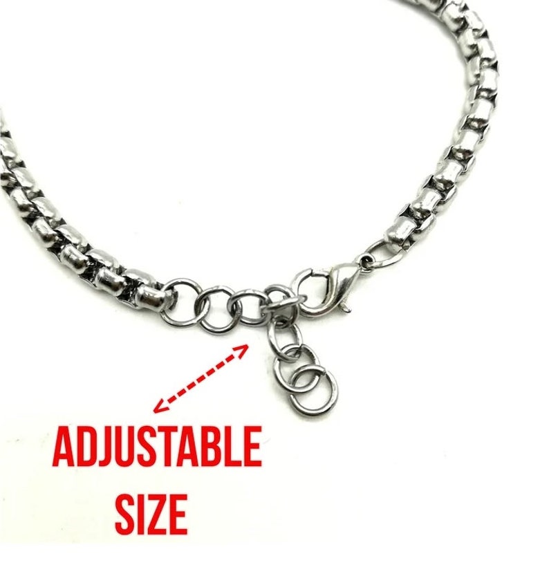 May include: A silver chain bracelet with an adjustable clasp. The bracelet is made of small, linked metal pieces. The clasp is a lobster claw style with a small chain attached to it. The text "ADJUSTABLE SIZE" is written below the bracelet.