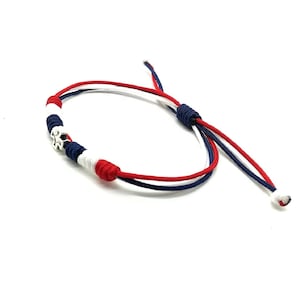 May include: A red, white, and blue braided bracelet with a silver star charm.