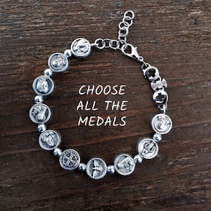 May include: Silver bracelet with a variety of religious medal charms. The bracelet has a lobster clasp closure. CHOOSE ALL THE MEDALS.