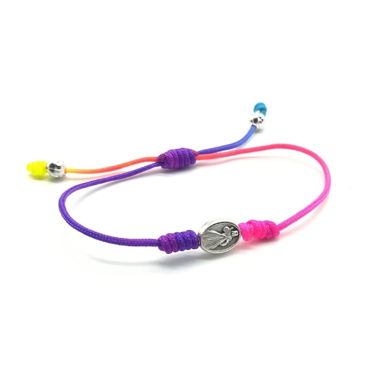 May include: A colorful braided bracelet with a silver charm featuring a religious figure. The bracelet is made with multiple strands of cord in shades of yellow, orange, red, purple, and pink.