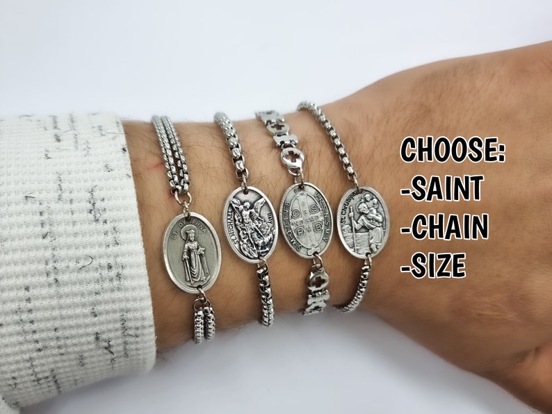 May include: A silver chain bracelet with a variety of oval-shaped charms featuring religious figures. The bracelet is shown on a person's wrist. CHOOSE: -SAINT -CHAIN -SIZE