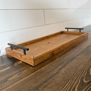 May include: A wooden serving tray with black metal handles. The tray is stained a dark brown color and has a rustic look.