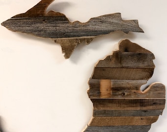 Op de afbeelding: Twee houten wandkunstwerken in de vorm van de staat Michigan. Het bovenste stuk is het Bovenschiereiland en het onderste stuk is het Onderschiereiland. Beide stukken zijn gemaakt van gerecycled hout met een rustieke afwerking.