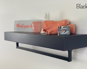 Puede incluir: Estante flotante negro con barra para toallas, que incluye un letrero decorativo que dice "Lávate las manos", una toalla rosa y una pastilla de jabón.