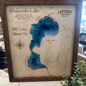 Puede incluir: Mapa de los lagos Madawaska, Maine, cortado con l&aacute;ser y enmarcado en madera, con contornos de profundidad en tonos azules. Incluye el texto: "287 Lake Shore Dr" y "Lakeside Cabin Rentals". La profundidad m&aacute;xima es de 10,67 metros.
