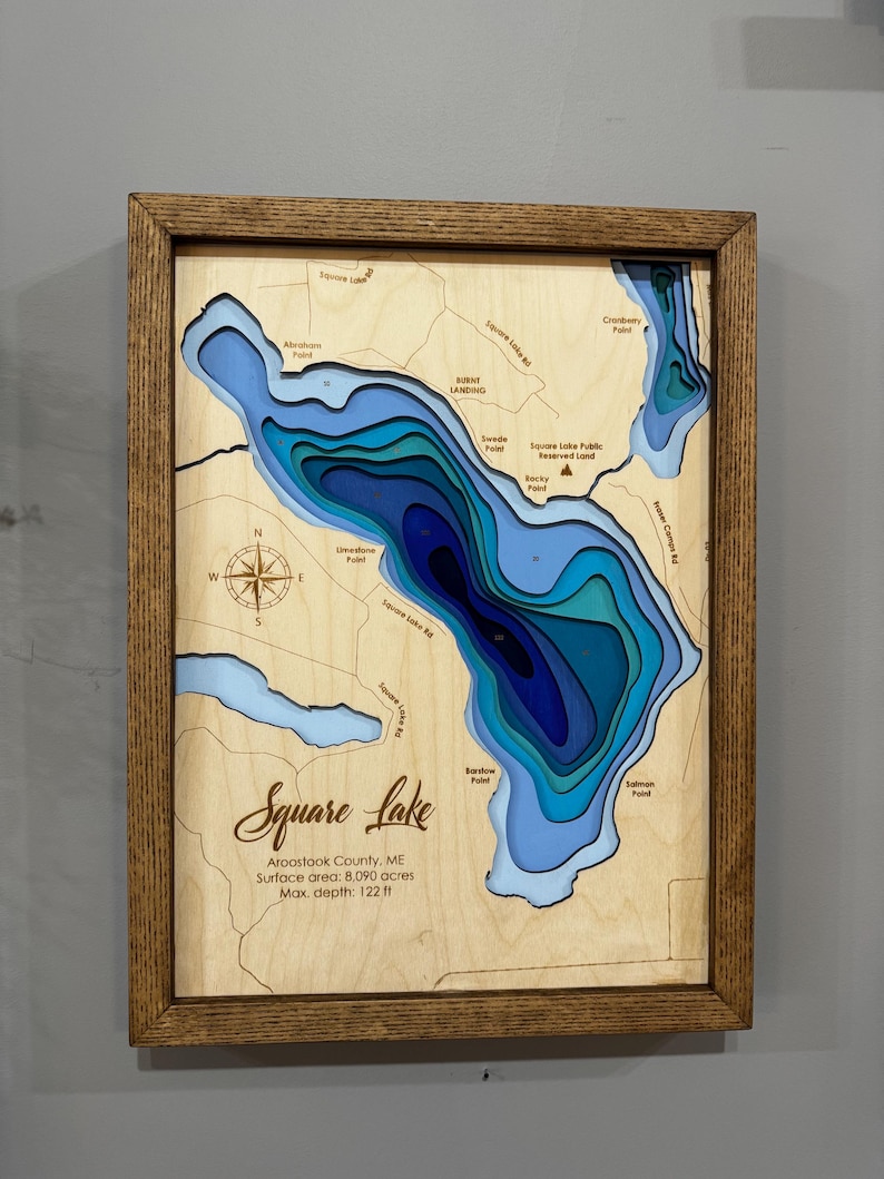 Puede incluir: Un mapa de madera enmarcado del lago Square en el condado de Aroostook, ME. El mapa presenta contornos azules y celeste en capas que representan la profundidad del lago. El texto incluye el nombre del lago, la superficie y una profundidad m&aacute;xima de 37,18 m.