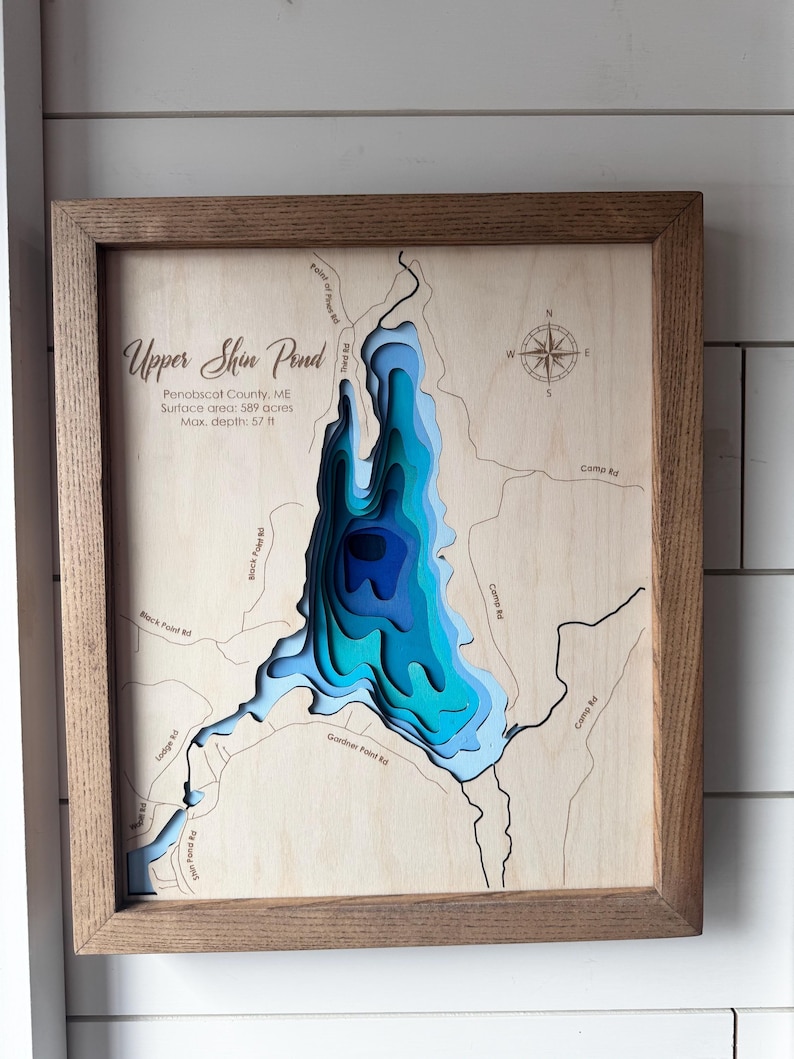 Puede incluir: Un mapa de madera enmarcado de Upper Shin Pond en el condado de Penobscot, ME. El mapa muestra la profundidad del estanque en capas de azul, con una superficie de 589 acres y una profundidad m&aacute;xima de 17,4 m. El marco es de color marr&oacute;n claro.