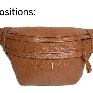 Puede incluir: Ri&ntilde;onera de cuero marr&oacute;n con superficie texturizada. La bolsa tiene forma curvada con cremallera y correa ajustable. El texto "Positions:" est&aacute; en la parte superior de la imagen y el n&uacute;mero "1" est&aacute; en la parte delantera.