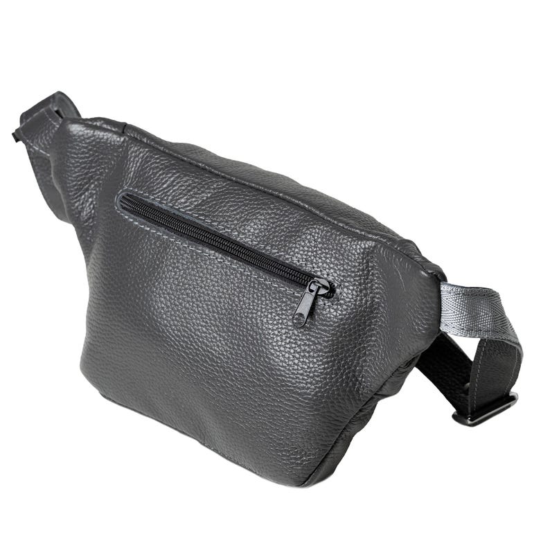 Puede incluir: Un bolso de cintura gris oscuro hecho de cuero texturizado. La bolsa presenta un cierre de cremallera negro y una correa ajustable negra. El bolso de cintura est&aacute; dise&ntilde;ado para usarse alrededor de la cintura o cruzado.