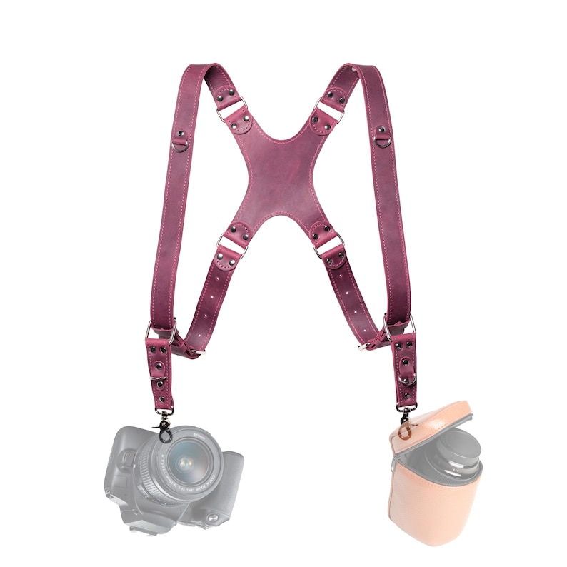 A purple leather camera strap with two camera attachments hanging from it.