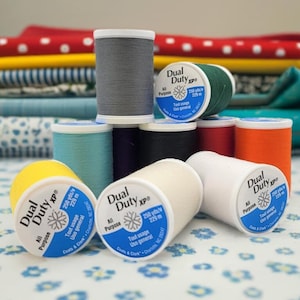 May include: A close-up of a variety of spools of thread in different colors, including yellow, white, gray, green, blue, and orange. The spools are labeled "Dual Duty xp" and "All Purpose".