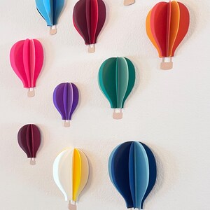 Handmade 3D paper hot air balloons hanging on a nursery wall.