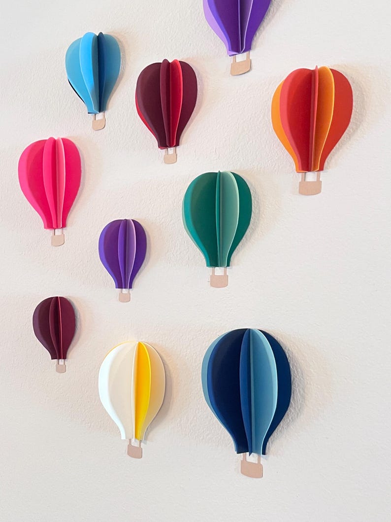 Handmade 3D paper hot air balloons hanging on a nursery wall.