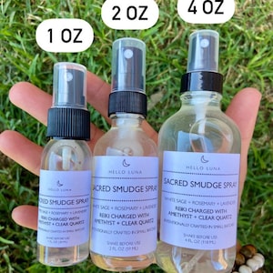 May include: Three glass spray bottles with black tops and labels that say "Hello Luna Sacred Smudge Spray". The bottles are labeled with different sizes: 1 oz, 2 oz, and 4 oz. The bottles are filled with a clear liquid.