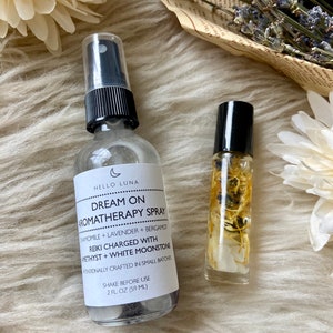 Puede incluir: Se muestran dos productos de aromaterapia: un frasco de spray transparente y un peque&ntilde;o frasco roll-on. El frasco de spray tiene una tapa negra y una etiqueta con el texto "Dream On Aromatherapy Spray". El roll-on contiene elementos bot&aacute;nicos visibles.